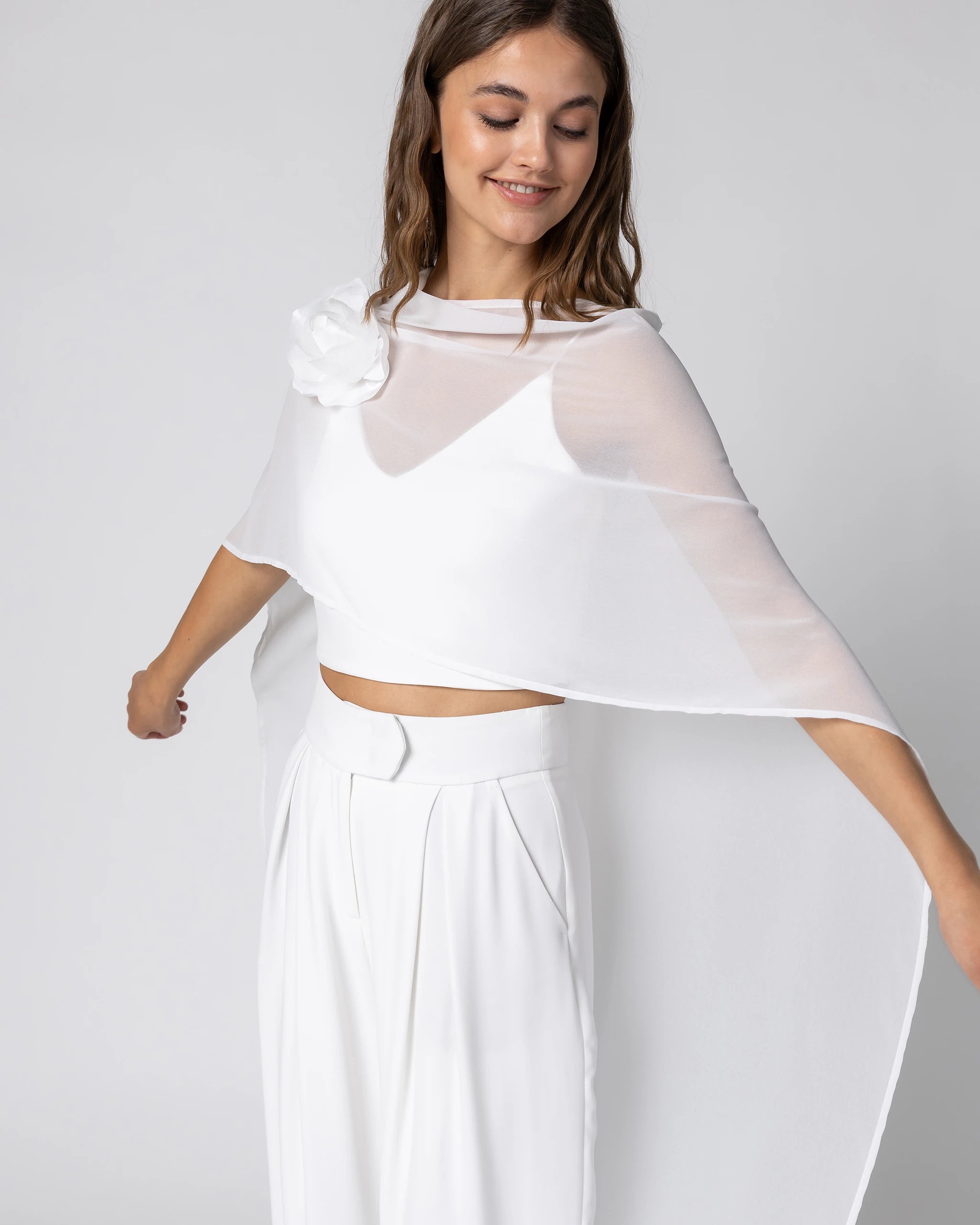 Braut in modernem Braut Jumpsuit mit Bralette Top, weiter Marlene Hose und Chiffon Cape mit Blütenbrosche Detailansicht Top