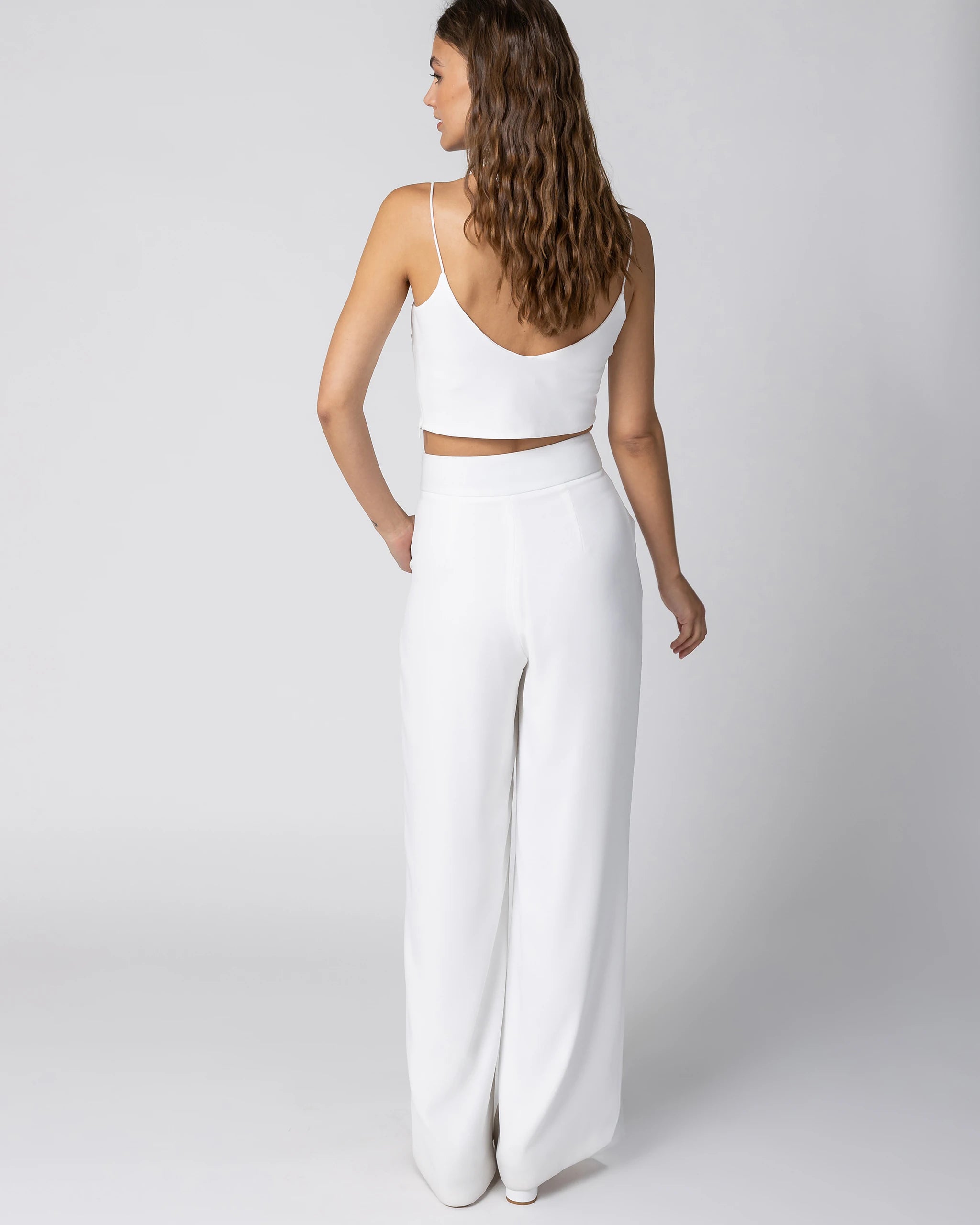 Braut in modernem Braut Jumpsuit mit Bralette Top und weiter Marlene Hose in Ivory Ansicht hinten