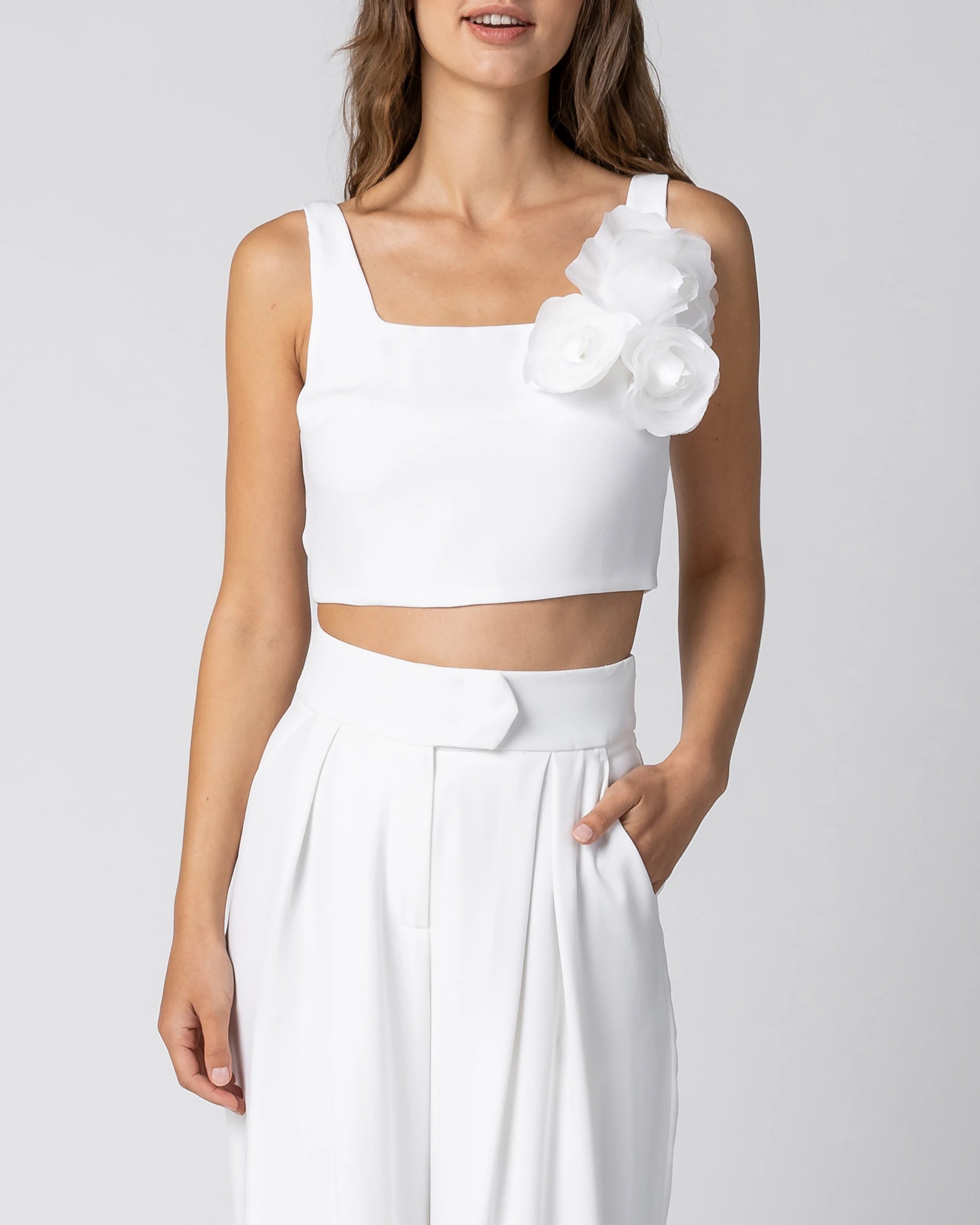 Braut in modernem Hosenanzug mit Crop Top, weiter Marlene Hose und Chiffonblume in Ivory Detailansicht
